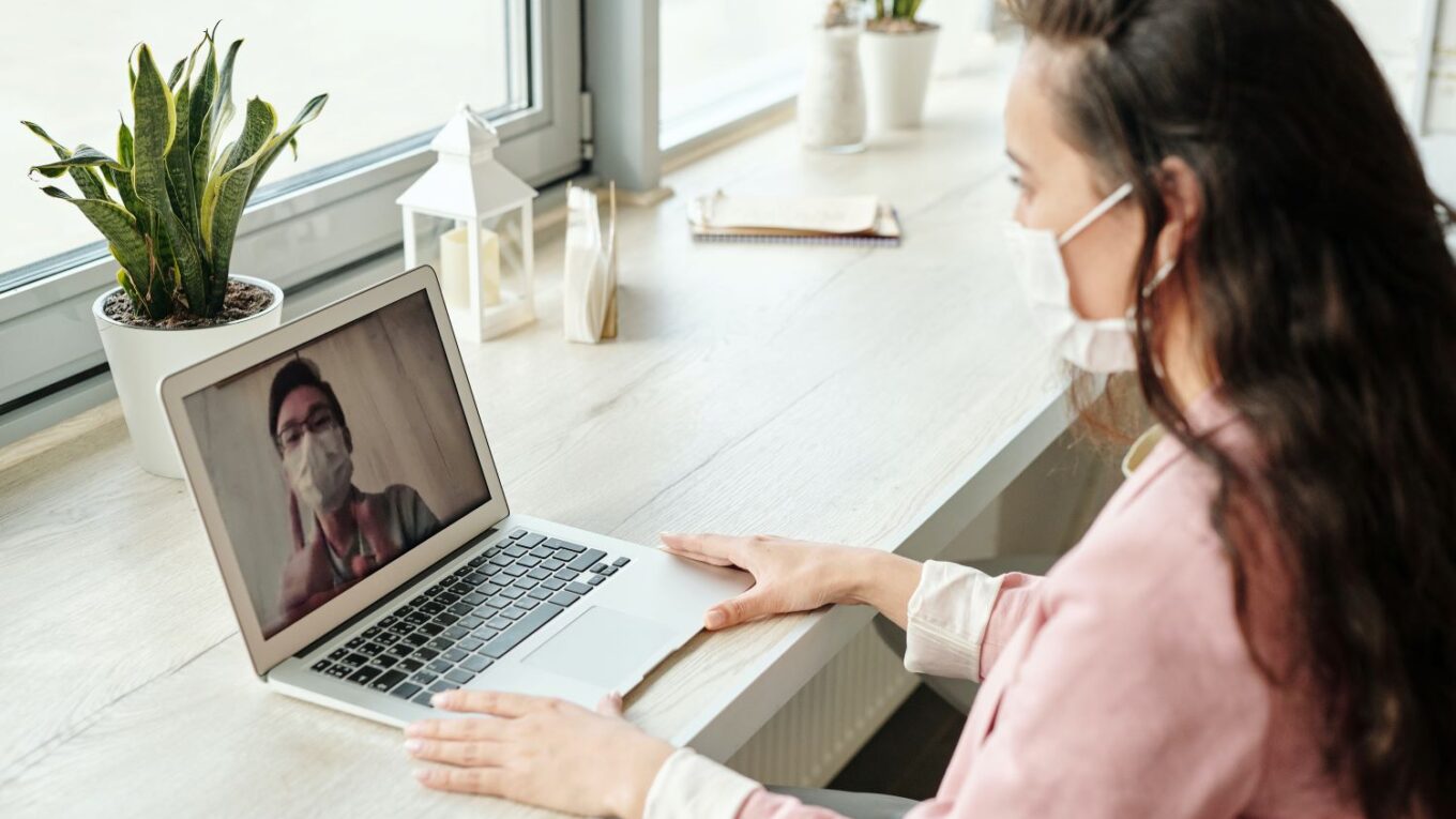 Woman doing an online consultation with a doctor, both wearing masks