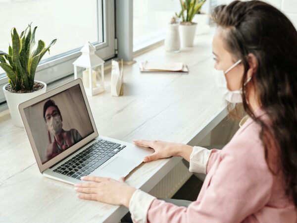 Woman doing an online consultation with a doctor, both wearing masks