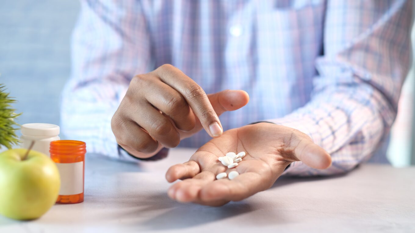 Man holding several pills in his hand