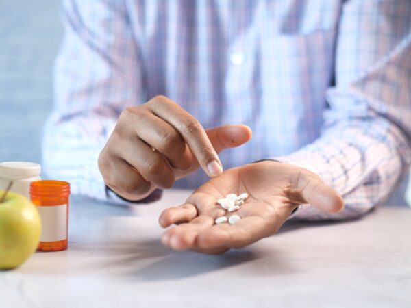 Man holding several pills in his hand