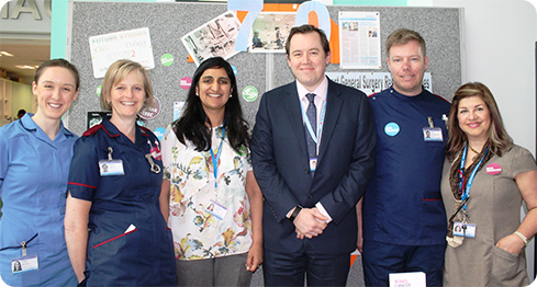 team smiling in front of stand